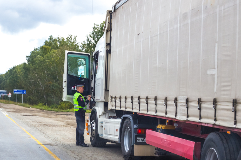 Enforcement officer inspecting a truck for DOT violations on a roadside