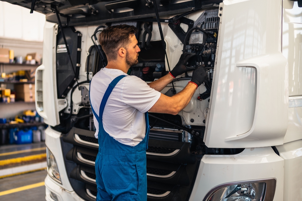 Technician working on truck engine part of fleet safety management